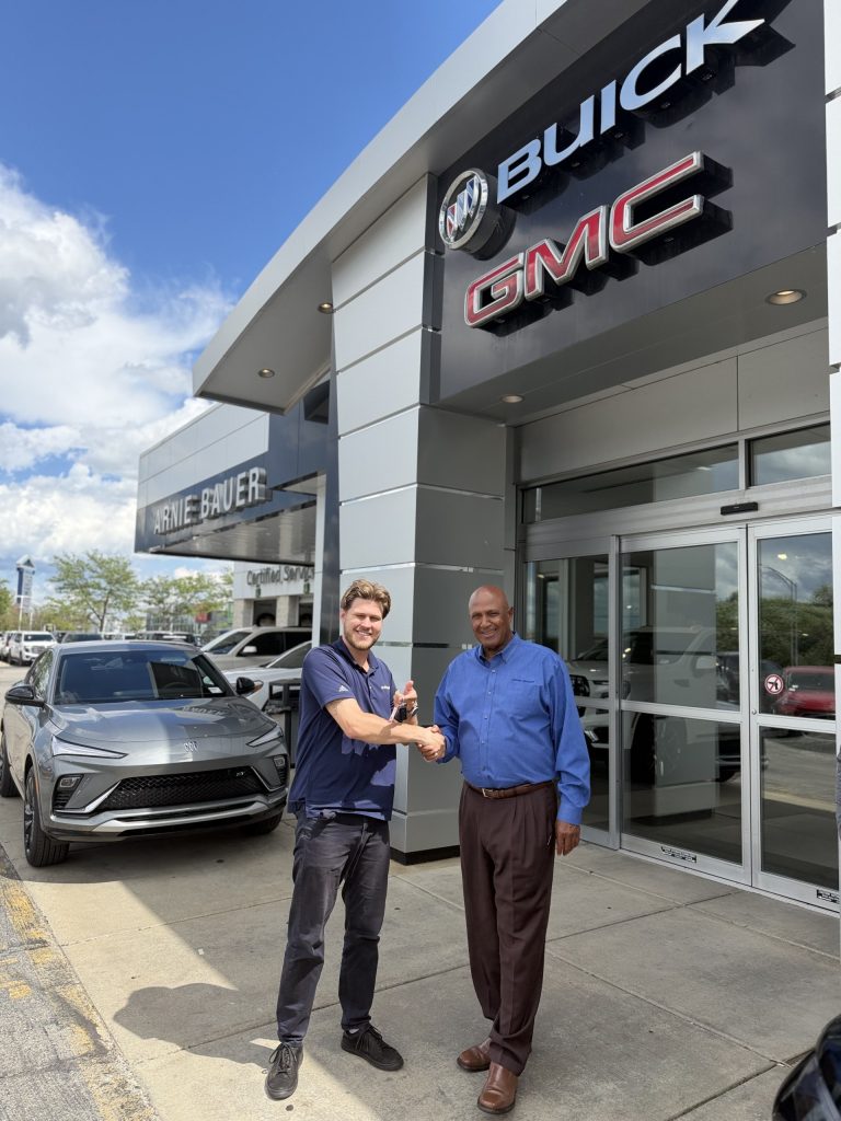 A happy customer is receiving keys to their new car after trading in a vehicle they still owed money on.